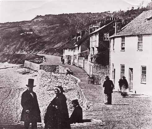 811edLyme2 The earliest photograph of The Walk, taken in the 1850s, probably even in the early 1850s. The Assembly Rooms are behind the photographer. The Walk is well gravelled, and the slope behind the beach very bare. The square sticking out from the path is the remains of West Fort, built in 1627 and removed in 1862.