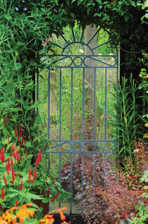A tall mirror set behind what appears to be a gate suggests additional distant interest while in fact it is a reflection of the garden from which it is viewed