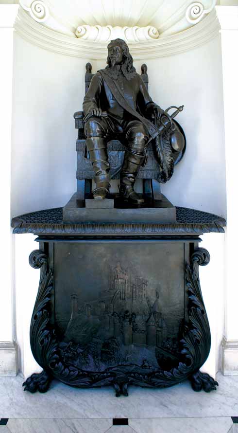 The statue of Charles I on the main staircase of Kingston Lacy, with the siege of Corfe Castle shown on the shield below